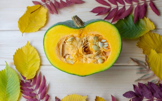 Cut ripe, yellow pumpkin on a wooden background with autumn leaves. Autumn background