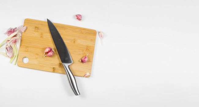 Closeup image of chief knife and garlic on wooden board banner