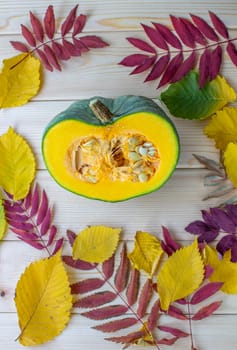 Cut ripe, yellow pumpkin on a wooden background with autumn leaves. Autumn background