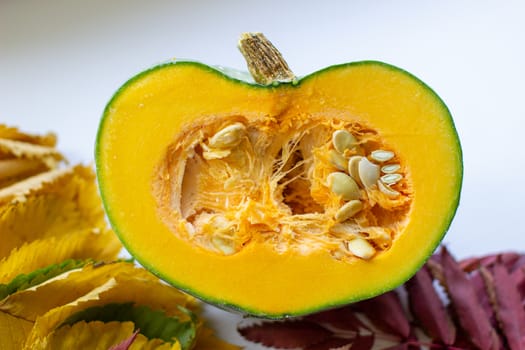 Cut ripe, yellow pumpkin on a wooden background with autumn leaves. Autumn background