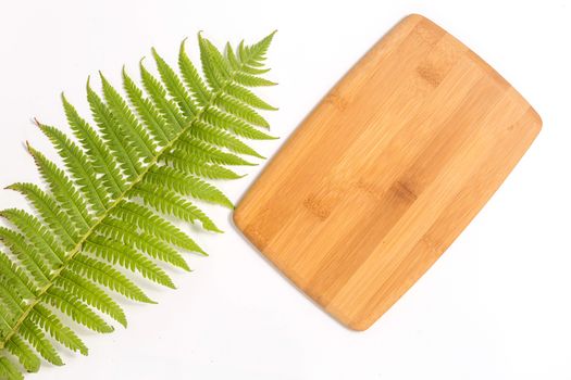 Bamboo Cutting Board with green leaf of fern on white background. Eco friendly housekeeping concept