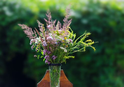 Bouquet of wild flowers in vase in a garden. Soft focus, beautiful bokeh