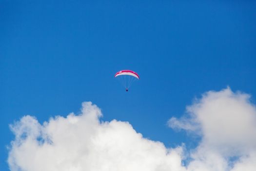 One paraglider is flying in the blue sky against the background of clouds. Paragliding in the sky on a sunny day.