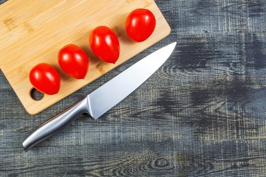 High Angle Still Life View of tomatoes and knife on Wooden Cutting Board on Rustic Wood Table