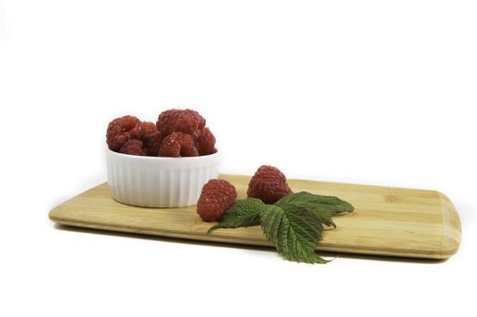 Ripe tasty bright Fresh raspberry in a wicker basket on a cutting board on a white background. High quality photo