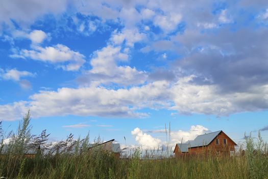 Large white clouds in the blue sky above a village in Russia.