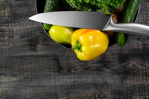 High Angle Still Life View of Knife and Wooden Cutting Board Surrounded by Fresh Herbs and Assortment of Raw Vegetables on Rustic Wood Table