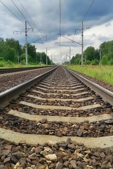 railway in a rural landscape. Evening, summer time, cloudy sky, vertical photo