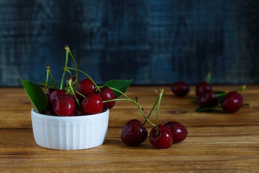 Fresh cherry on plate on wooden blue background. fresh ripe cherries. sweet cherries.