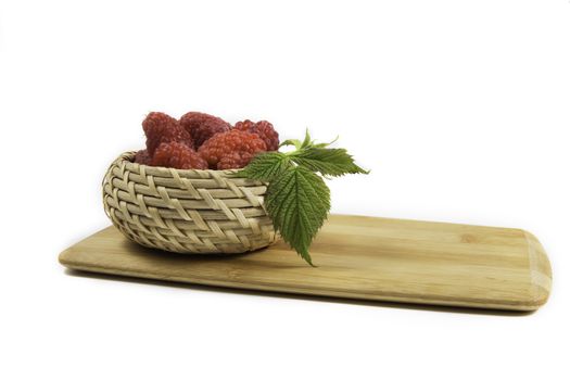 Ripe tasty bright Fresh raspberry in a wicker basket on a cutting board on a white background. High quality photo