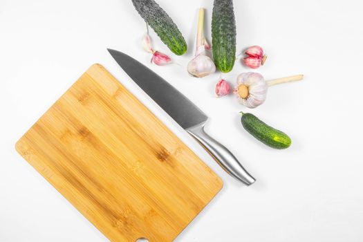 Closeup image of chief knife , garlic and cucumber on white table
