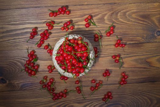 red currant berries in a ceramic bowl on a rustic wooden background. close up and selective focus