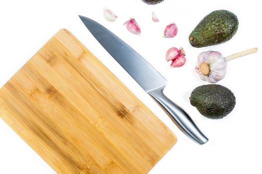 Closeup image of chief knife, garlic and avocado on white table