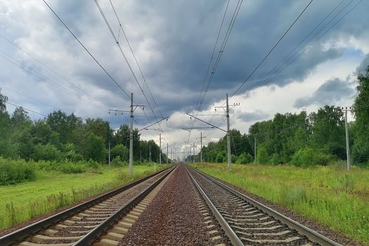 railway in a rural landscape. Evening, summer time, cloudy sky