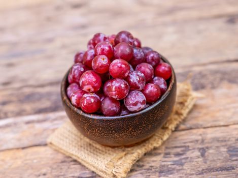 Red grape fruit in wooden bowl on blurred background