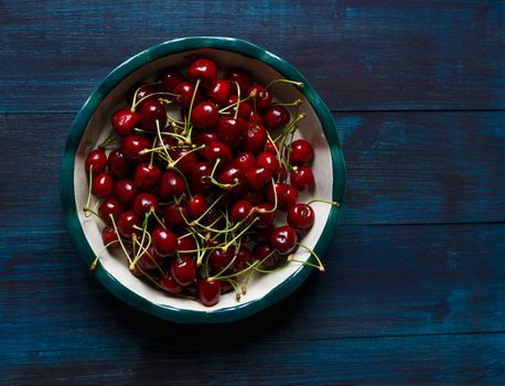 Fresh cherry on plate on wooden blue background. fresh ripe cherries. sweet cherries.