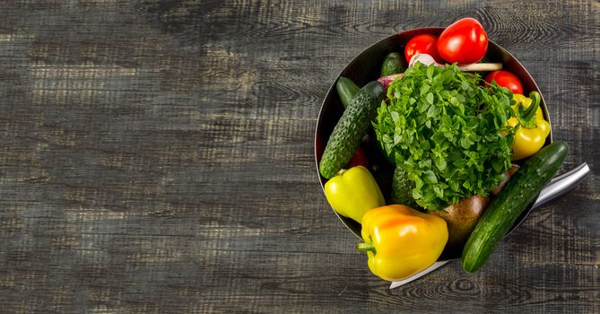 High Angle Still Life View of metal bowl Surrounded by Fresh Herbs and Assortment of Raw Vegetables on Rustic Wood Table banner