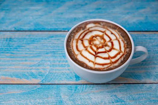 Latte coffee in a cup of coffee on blurred wooden background