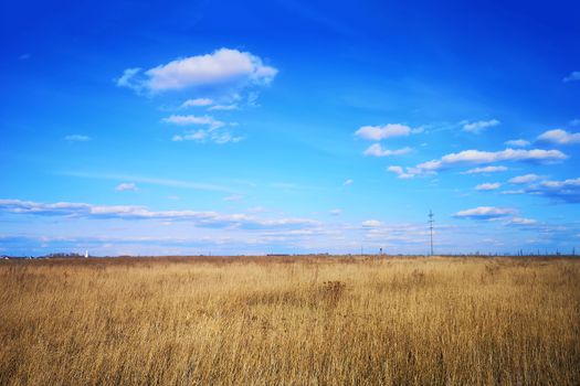 Large white clouds in the blue sky above a village in Russia.