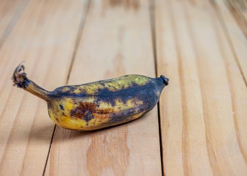 Rootten banana on wooden blurred background