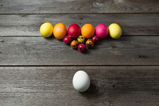 Hand painted easter eggs arranged like for billiards on wooden background. Easter background with space for a text.