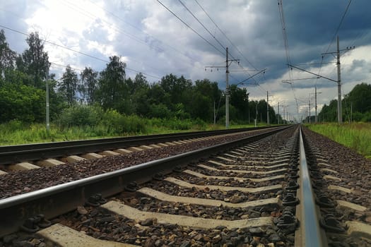 Railroad Tracks Against dark Cloudy Sky in a rural landscape. Evening, summer time