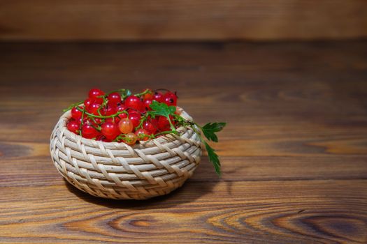 red currant berries in a ceramic bowl on a rustic wooden background. close up and selective focus