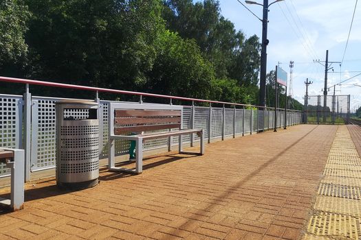 Railway station with benches and trash cans.