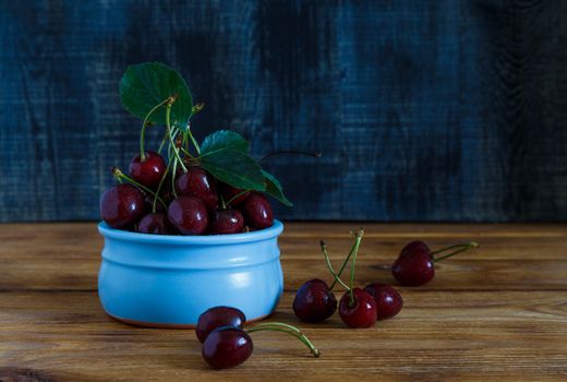 Fresh cherry on plate on wooden blue background. fresh ripe cherries. sweet cherries.