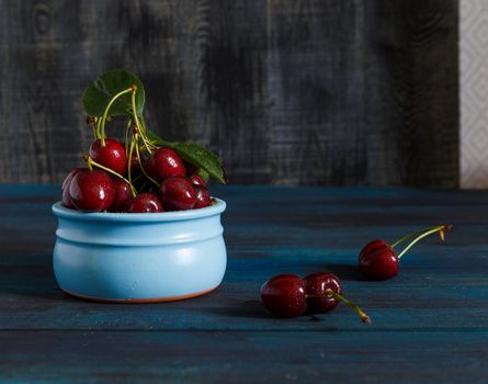 Fresh cherry on plate on wooden blue background. fresh ripe cherries. sweet cherries.