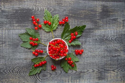 red currant berries in a ceramic bowl on a rustic wooden background. close up and selective focus