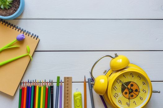 Back to school concept school office supplies on a white wooden background copy space of papers, pencils, alarm clock and tablet.