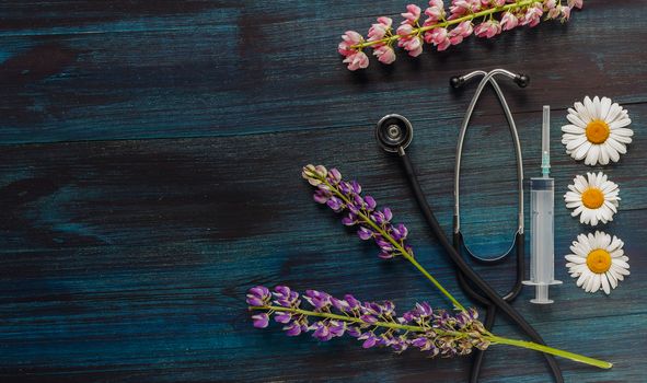 Still life made of stethoscope, syringe with a needle, medical face mask and flowers. Coronavirus, COVID-19 quarantine concept, second wave. Medical supplies, medical equipment concepts