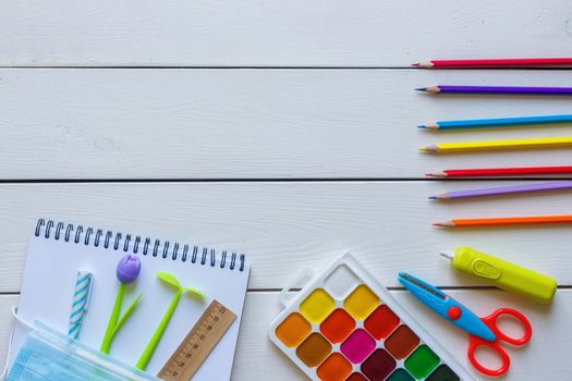 Back to school concept school office supplies on a white wooden background copy space. Education during self isolation on quarantine. Coronavirus concept.