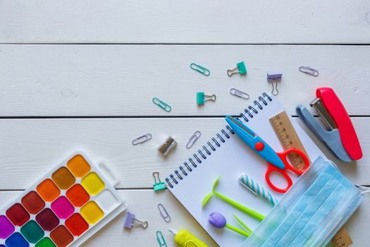 Back to school concept school office supplies on a white wooden backgrounf copy space. Education during self isolation on quarantine. Coronavirus concept.