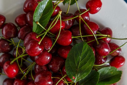 Fresh cherry on plate on wooden blue background. fresh ripe cherries. sweet cherries.