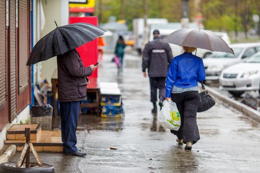 A man walks under an umbrella during the rain, having his face off the camera.