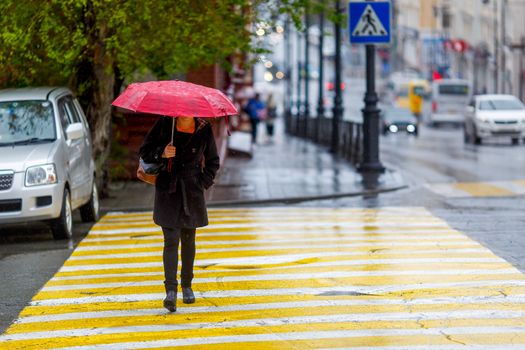 A man walks under an umbrella during the rain, having his face off the camera.