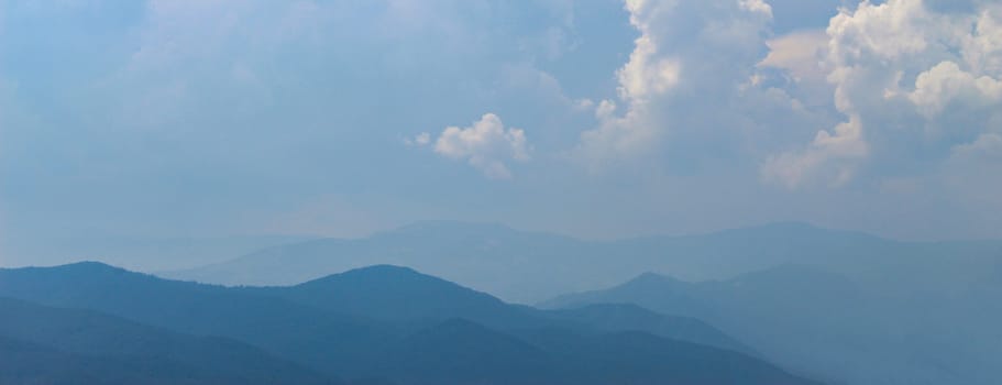 Banner. Blue silhouette of a mountain in the distance, with clouds in the blue sky. Mountains and hills in the distance. Bosnia and Herzegovina.