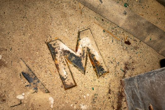 The Letter M From a Sign in an Old Abandoned Building Laying in Dust and Debris