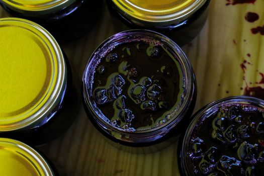 Homemade chokeberry jam in jars. Full jars of homemade chokeberry jam on a tray. Aronia jam. Zavidovici, Bosnia and Herzegovina.