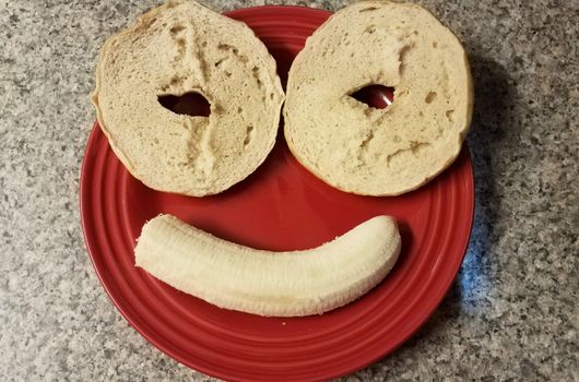 smiling face with bagels and banana on red plate
