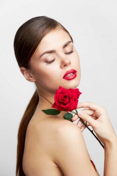 Brunette with bare shoulders Eyes closed flower charm red lips light background