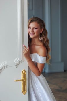 Bride in a beautiful white wedding dress peeks out of the door.
