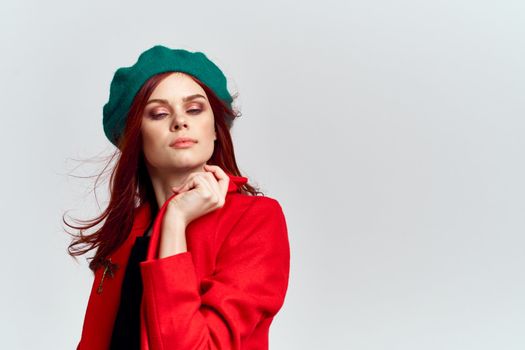 Woman in red coat and in green hat on isolated background cropped model with Copy Space emotions. High quality photo