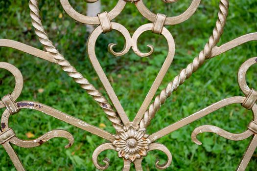 Forged elements on a garden bench in the shape of a heart.Garden wrought iron furniture in the garden.