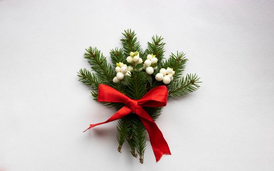 Christmas bouquet with fir branches, red bow and white dogwood berries on a white background . Christmas card. The theme of a winter holiday. Happy New Year.