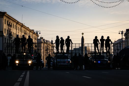 Riot police blocking the road for protesters. The army is blocking the city. Silhouettes of soldiers