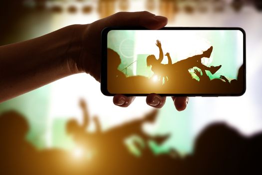 Stage diving. Crowd surfing during a musical performance. Silhouette of man.