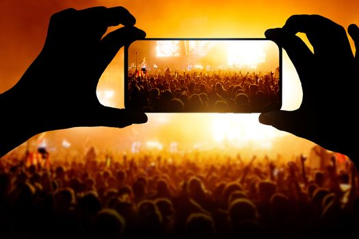 silhouettes of concert crowd in front of bright stage lights